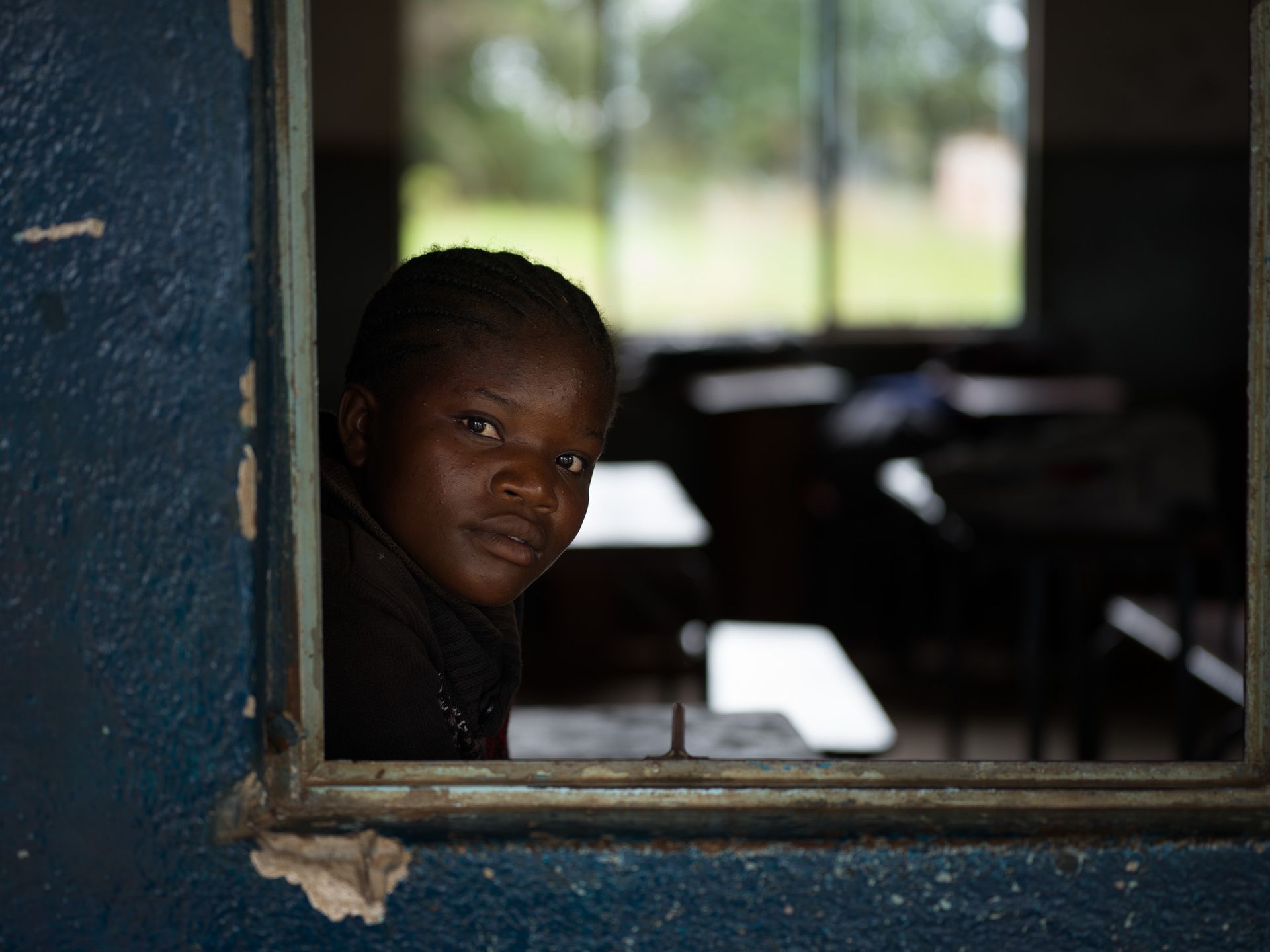 A girl looks through a classroom window, Meheba B Day Secondary School, Zambia
